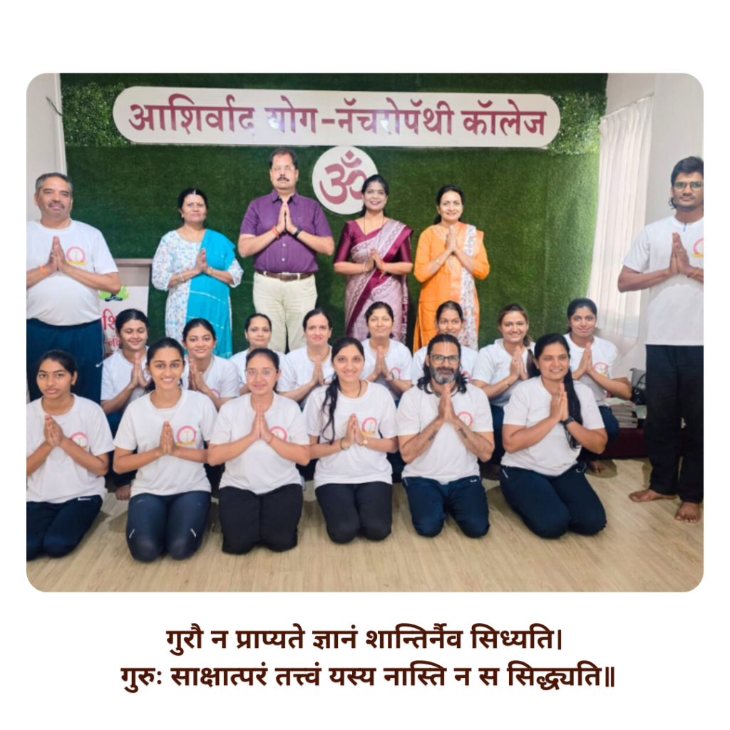 Group photo of yoga students and their teacher standing together, smiling in a natural outdoor setting, representing unity, discipline, and the spirit of yoga learning